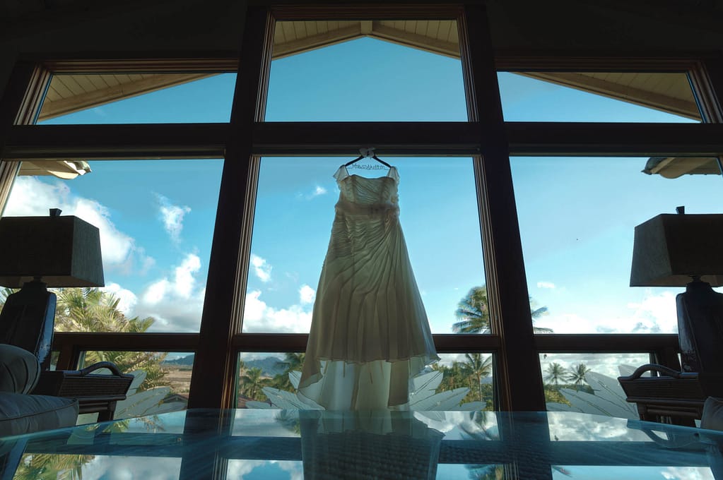 Wedding dress hung up in large living room window.