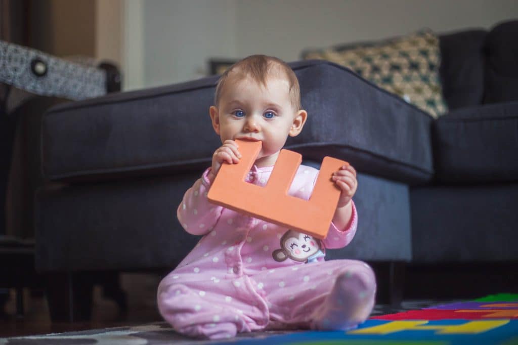 Toddler chewing on a letter.