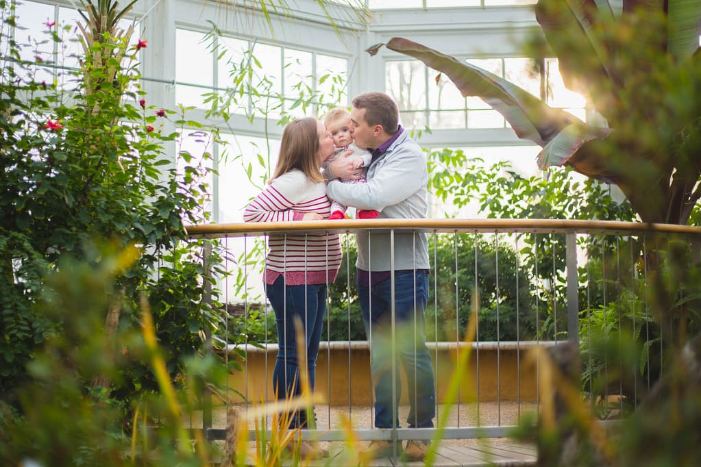 Parents kissing toddler.