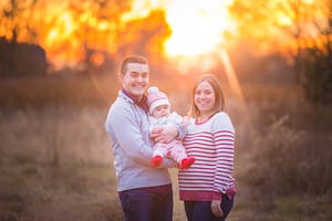 Adorable mother and father posing and holding their daughter.