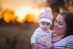 Mother holding daughter with sunset behind.