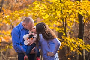 Parents kissing their daughter.